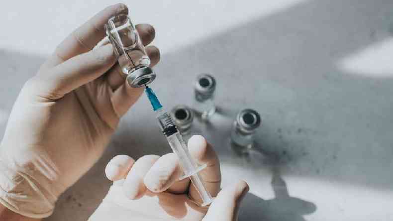 Profissional de sade tirando vacina de ampola