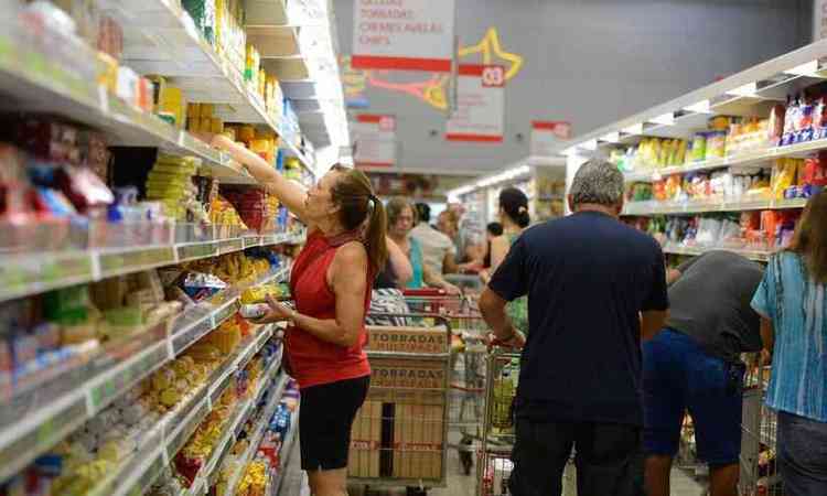 pessoas compram produtos ultraprocessados em um corredor de um supermercado