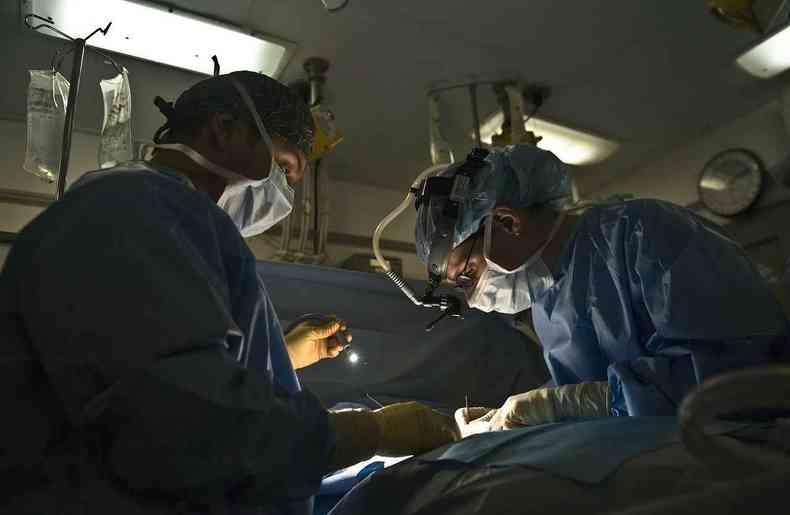 médicos operam em sala de cirurgia 