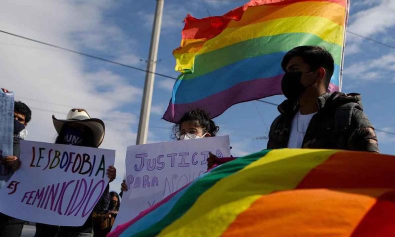 Manifestantes com cartazes contra a lesbofobia e com bandeira nas cores do arco-ris