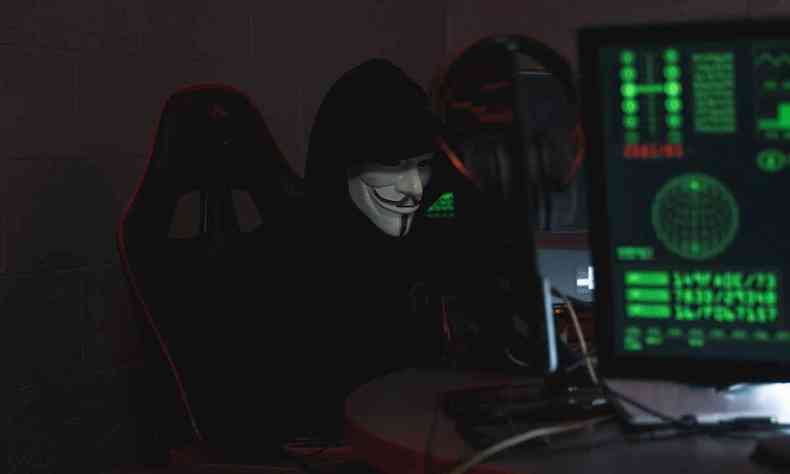 Homem mascarado usando o computador 
