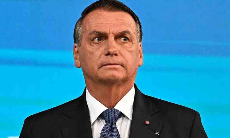 Jair Bolsonaro. Ele  um homem branco, de cabelos grisalhos, e usa terno. Ele est centralizado na foto e olha para a lateral a sua direita