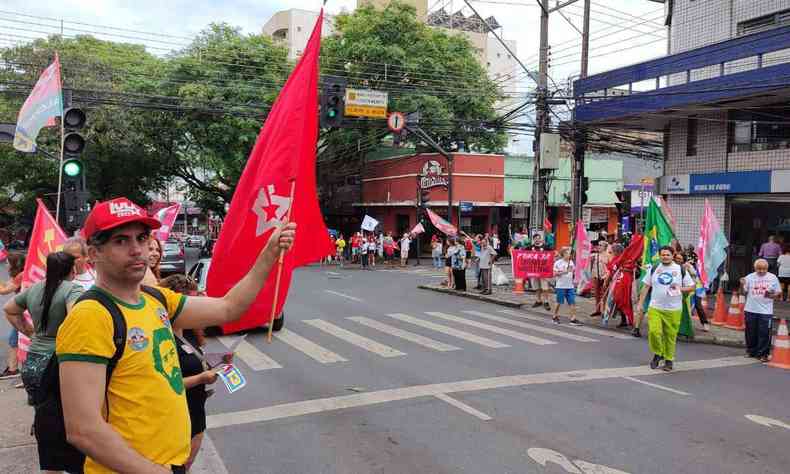 Apoiadores de Lula, de vermelho, seguram bandeiras na Avenida do Contorno, no Bairro Floresta