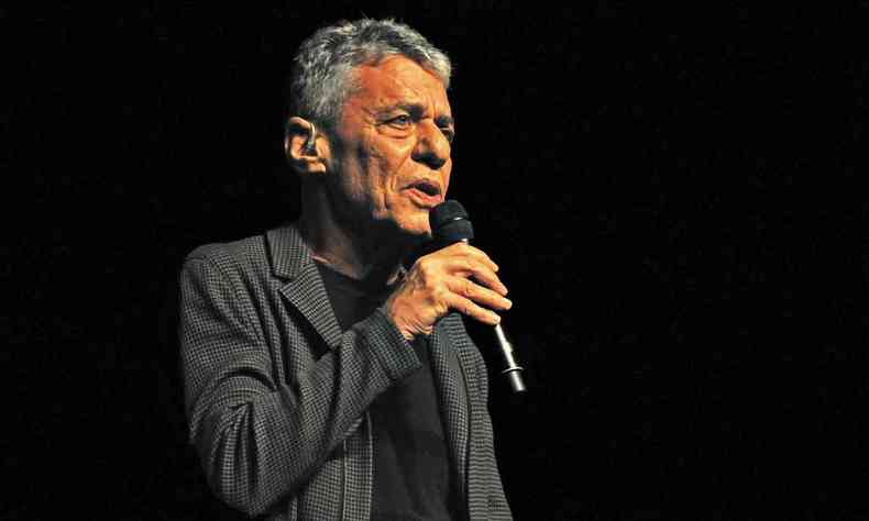Chico Buarque, de camisa de manga longa preta, empunha microfone no palco do Palcio das Artes