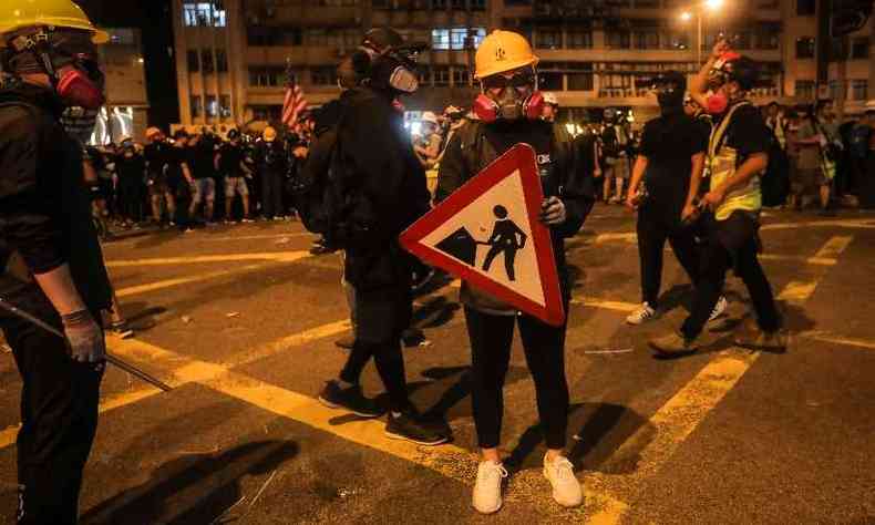 Manifestante segura sinal de trnsito como escudo aps marcha contra polmica lei de extradio(foto: VIVEK PRAKASH / AFP)