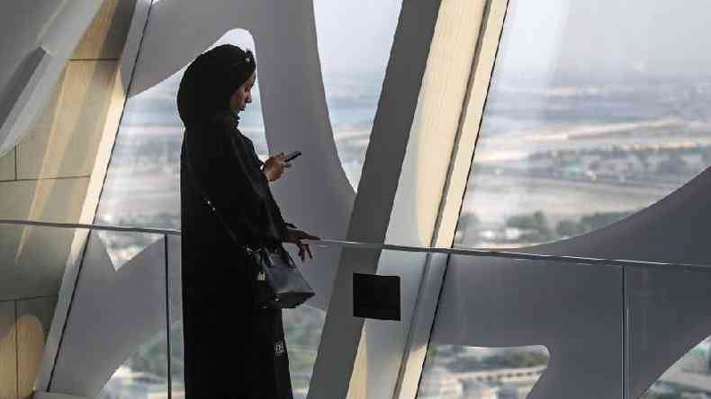 Mulher olha para o celular na cidade de Dubai, nos Emirados Árabes Unidos