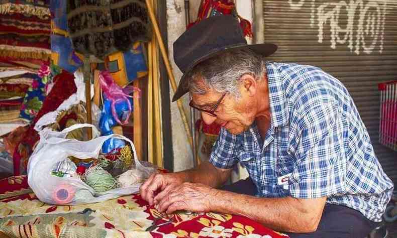 Homem idoso tece tapete em Tel-Aviv, Israel