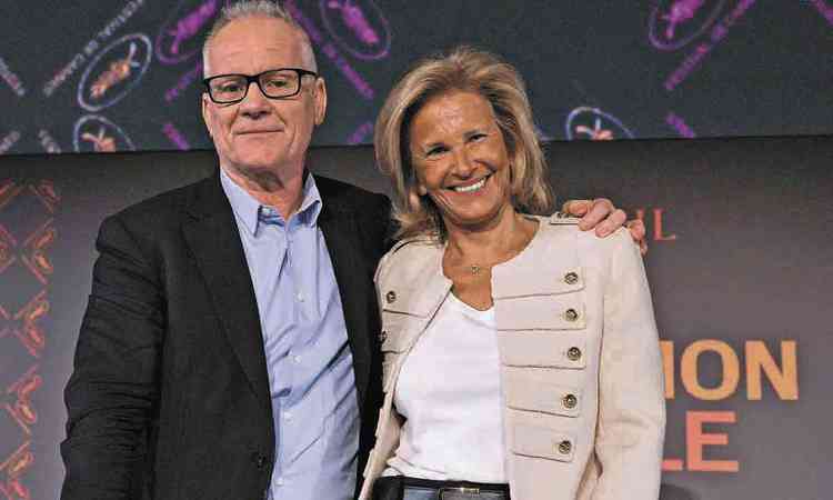Os diretores do Festival de Cannes Thierry Fremaux e  Iris Knobloch abraados, de p, no palco
