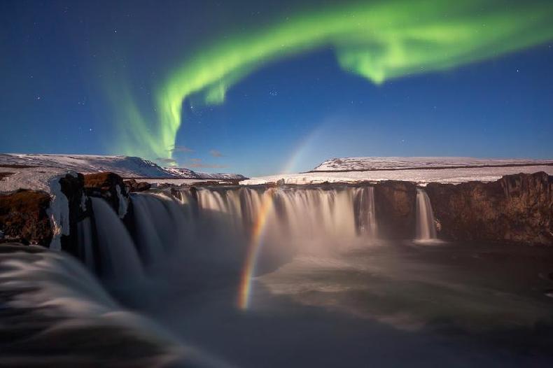 A aurora boreal e um arco-ris lunar visto acima da cachoeira Godafoss, na Islndia