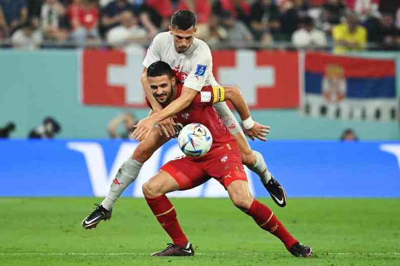 Jogadores sérvio e suíço disputam bola durante partida na Copa do Catar