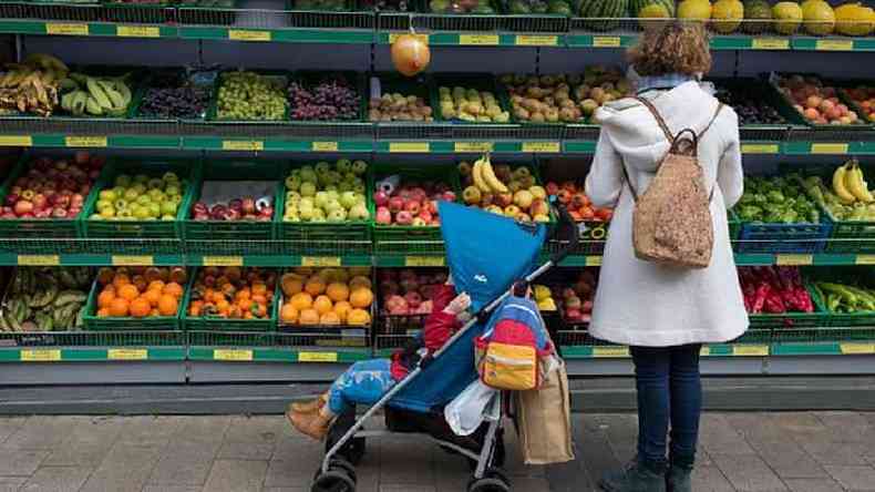 Mulher com beb escolher frutas em mercado