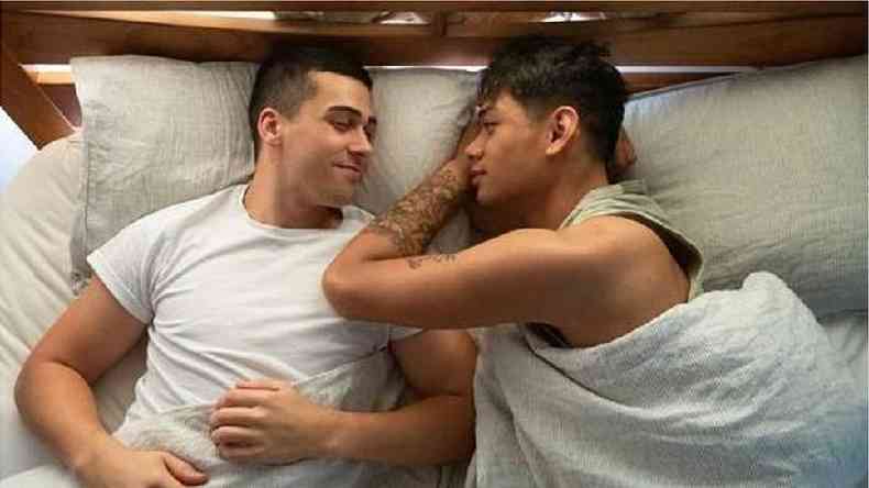 Dois homens deitados na cama se olhando