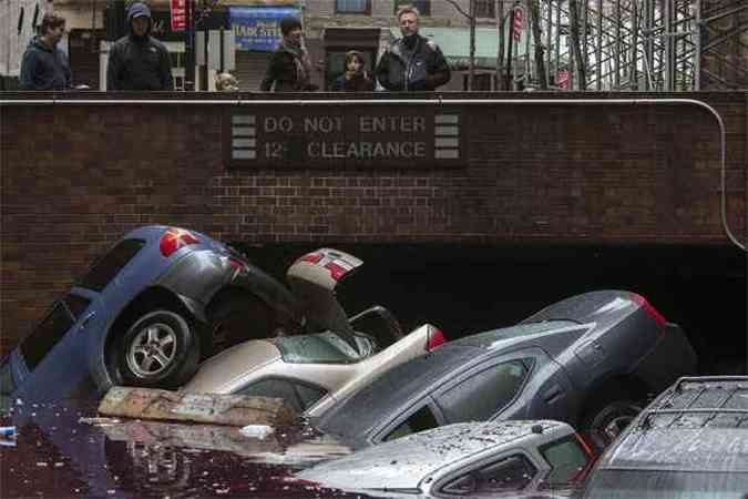 Moradores ficam de p observando os veculos submergirem em um estacionamento no Distrito de Lower Manhattan, na cidade de Nova York(foto: REUTERS/Adrees Latif )