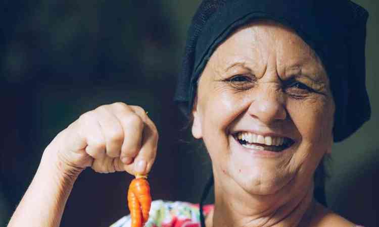 Chef Beth Coutinho sorri e segura pequenas cenouras