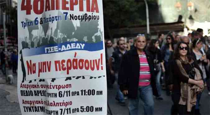 Jornalistas participam de protesto em Atenas, no primeiro plano um cartaz chama os trabalhadores para uma paralisao nos dias 6 e 7 de novembro (foto: AFP PHOTO / LOUISA GOULIAMAKI/Greece Out )