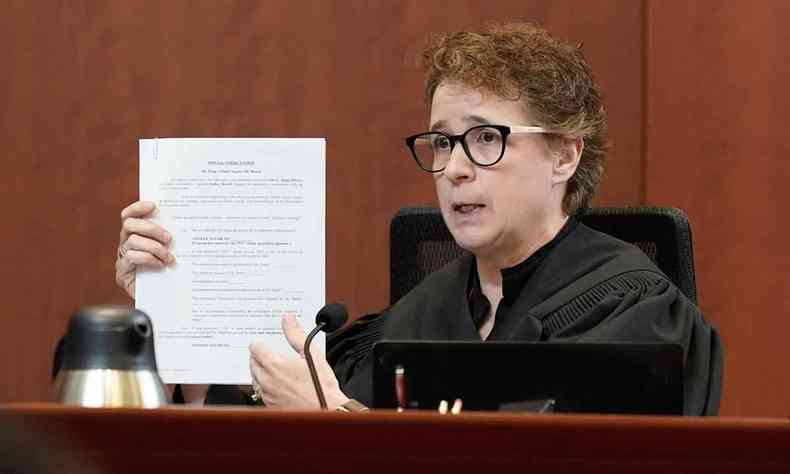 De toga e culos, sentada em sua cadeira, a juza Penney Azcarate exibe documento aos jurados do caso Johnny Depp x Amber Heard
