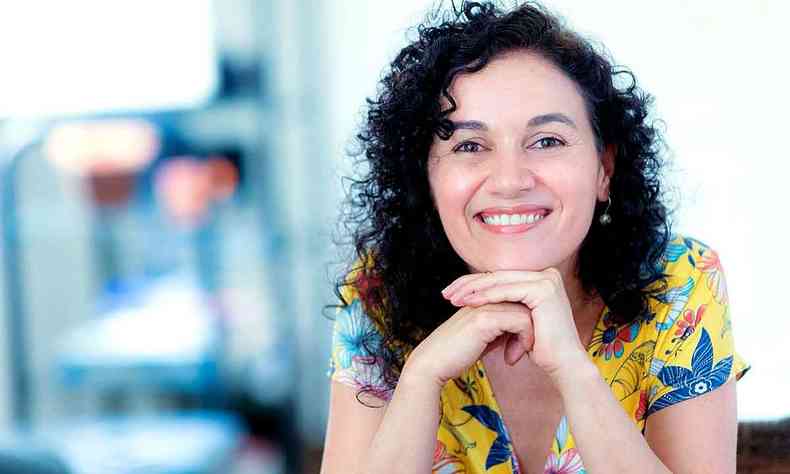 A poeta mineira Adriane Garcia sorri, com as mos no queixo 