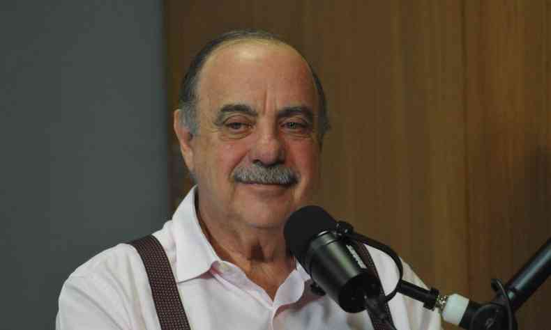 Fuad Noman, de camisa rosa e suspensrios bord, sorrindo diante de um microfone 