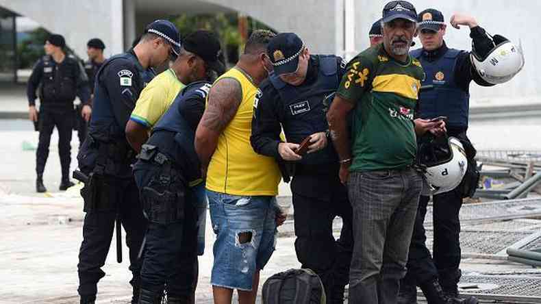 Homens e policiais enfileirados em rea externa de Braslia