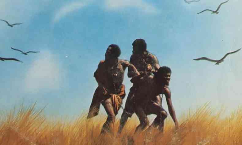 Três escravos correm e olhem para trás na cena do filme Chico Rei