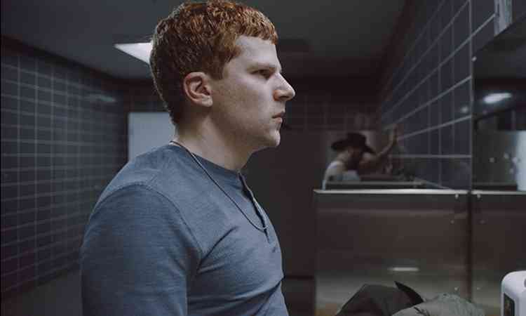 Com semblante carregado, ator Jesse Eisenberg se olha em espelho de banheiro masculino em cena do filme Manodrome
