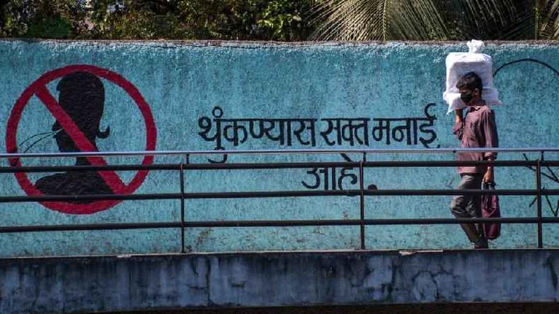 Um homem usa mscara como proteo a prximo a uma mensagem pintada em um muro pedindo para as pessoas no cuspirem. Foto tirada em 18 de maro de 2020 em Mumbai, ndia.
