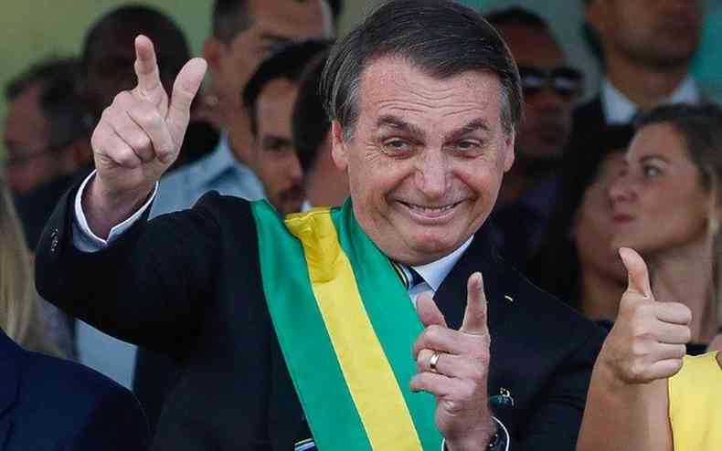 Presidente Jair Bolsonaro com faixa presidencial fazendo smbolo de arma com a mo