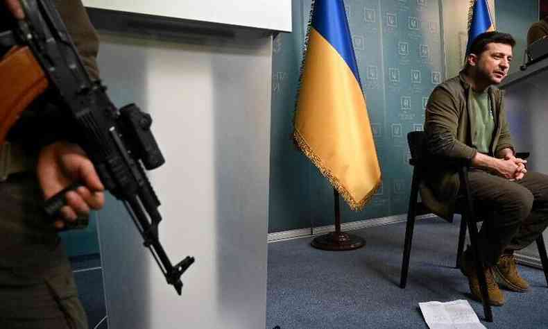 Metralhadora nas mos de um homem que protege o presidente ucraniano Zelensky durante pronunciamento