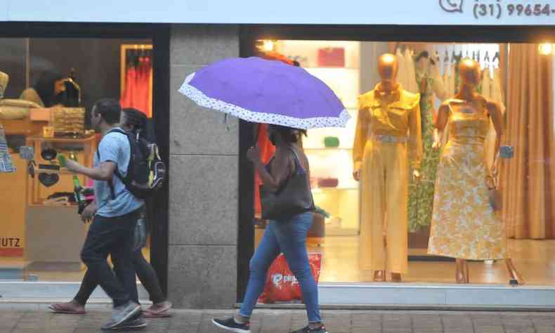 Pessoas andam nas ruas de BH com sombrinhas e guarda-chuvas