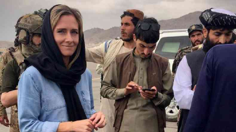 A jornalista Charlotte Bellis, uma mulher branca com hijab, ao lado de oficiais do Taleb no Afeganisto