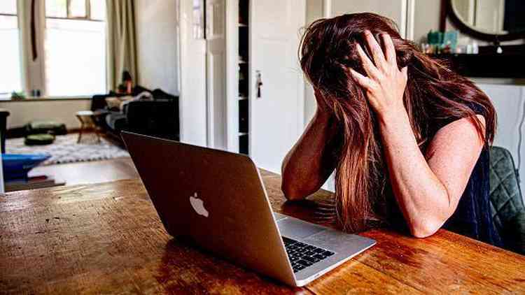 Mulheres com segurando a cabeça com as mãos em frente a um computador