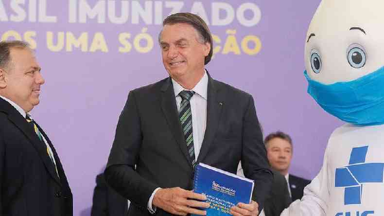 Bolsonaro (ao centro) recebe do ministro da Sade, Eduardo Pazuello ( esquerda), e do personagem Z Gotinha ( direita) o Plano Nacional de Operacionalizao da Vacinao contra a covid-19 em evento no dia 16 de dezembro de 2020(foto: Isac Nbrega/PR)