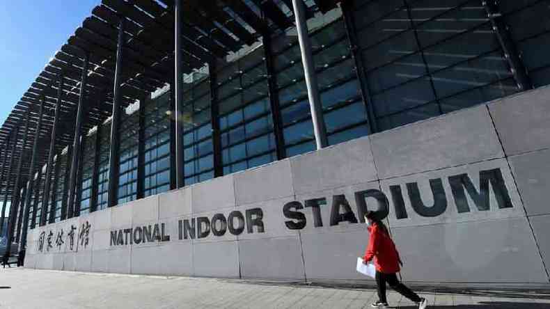 Mulher passa pelo National Indoor Stadium antes de uma partida de hquei no gelo, parte de um evento-teste dos Jogos Olmpicos de Inverno de Pequim em 2022, em Pequim, em 10 de novembro de 2021