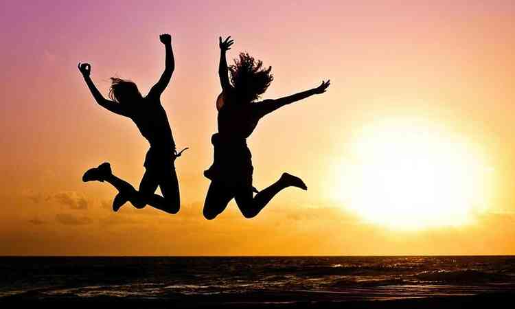 silhueta de duas mulheres pulando ao pr do sol 