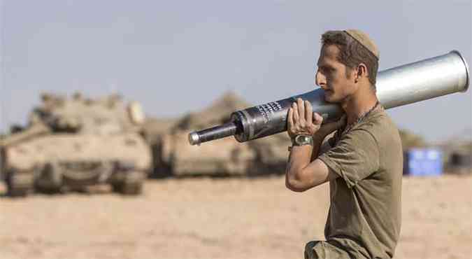 Soldado israelense carrega munio para os tanques de guerra posicionados na fronteira com Gaza(foto: AFP PHOTO/JACK GUEZ)