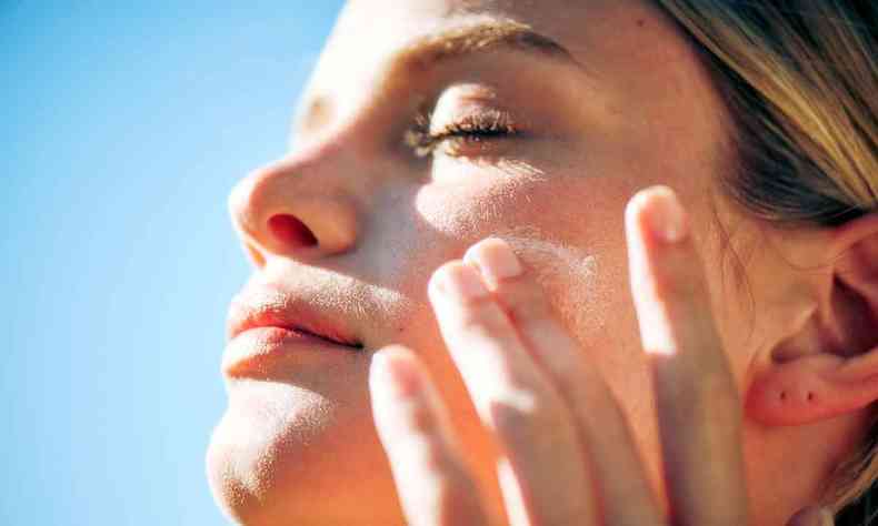 mulher passa protetor solar no rosto 