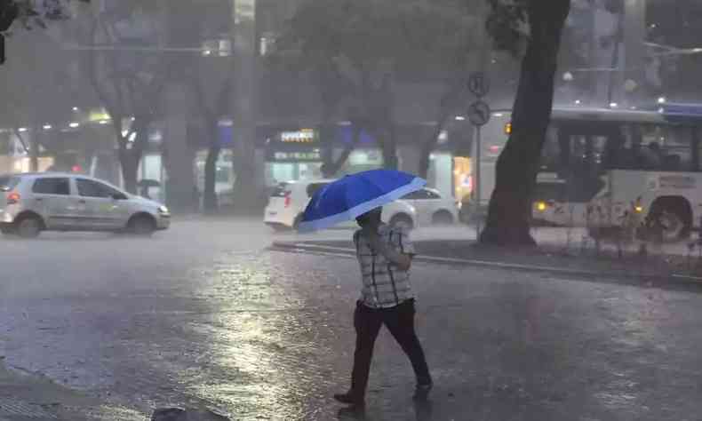 homem atravessa a rua com guarda-chuvas