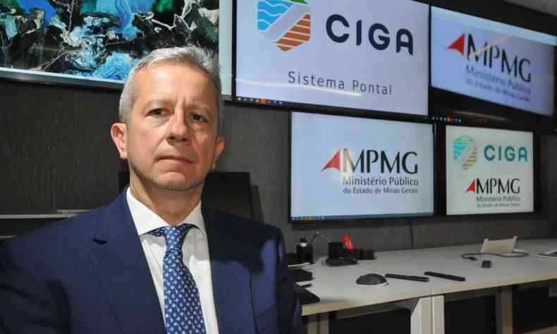 promotor Carlos Eduardo ao lado de monitores com as palavras CIGA e a sigla MPMG 