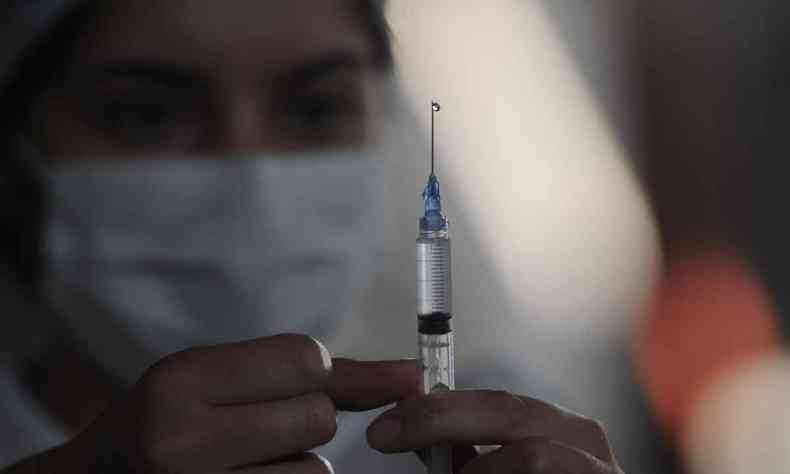 enfermeira em BH mostra ampola com vacina