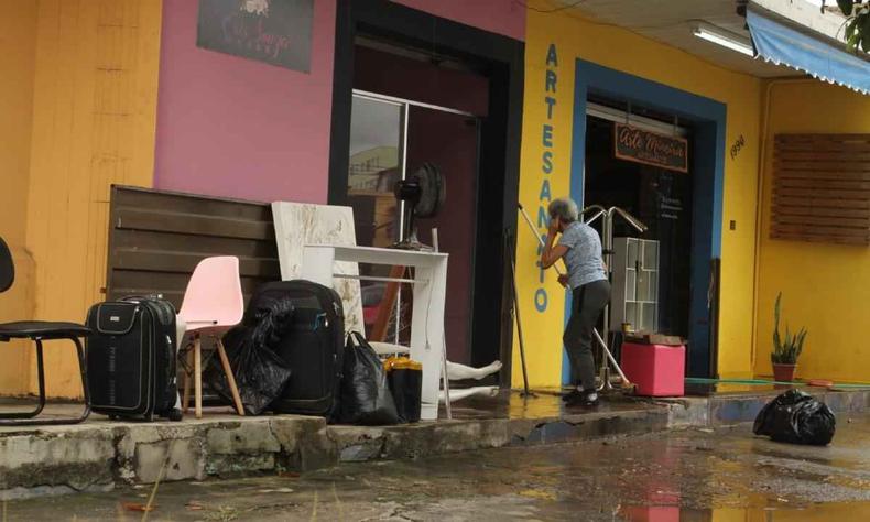Comrcio com entulhos na porta e pessoa limpando