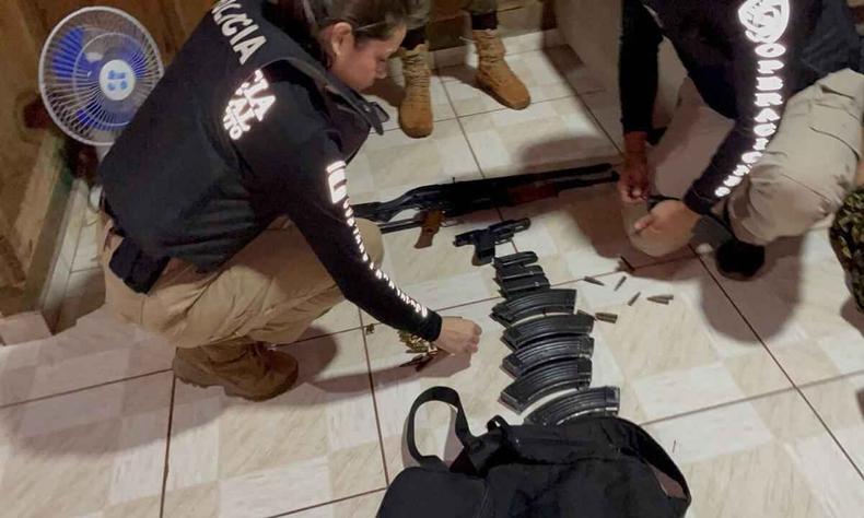 Prisões ocorreram em Pedro Juan Caballero, no Paraguai. Armas de grosso calibre foram encontradas com os suspeitos(foto: Divulgação/Polícia Civil) Imagem de uma apreensão de armas no Paraguai mostra armas e carregadores no chão, com policiais verificando
