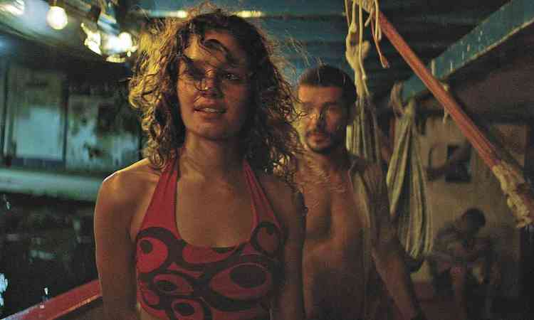 A atriz Sophie Charlotte em primeiro plano e o ator Daniel Oliveira, ao fundo, de p num barco, em cena de O rio do desejo