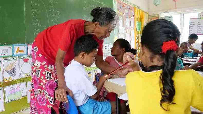 Professor corrigindo o trabalho de uma criana em uma escola em Tuvalu