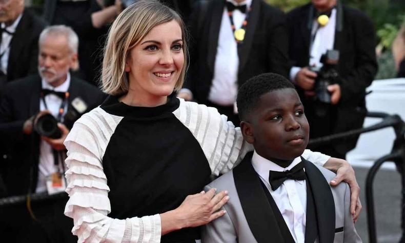 A diretora Léonor Serraille e o ator Sidy Fofana chegam ao festival para a exibição de 'Un petit frère'(foto: Loic Venance/AFP) A diretora Léonor Serraille com as mãos nos ombros do jovem ator Sidy Fofana, durante o Festival de Cannes