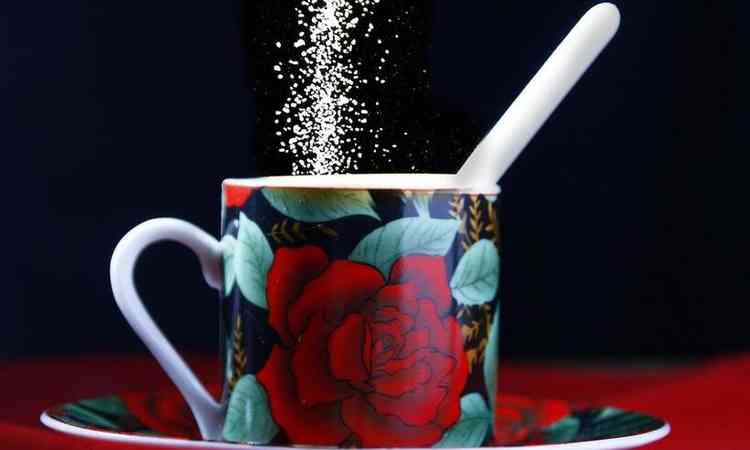 xcara de caf estampada de flores recebendo um adoante em p