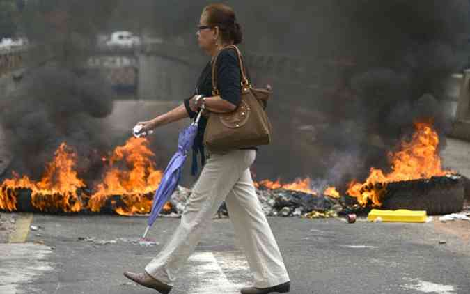 Mulher caminha ao lado de barricada em Caracas. Cenrio comum na Venezuela nas ltimas semanas(foto: Raul Arboleda/AFP)