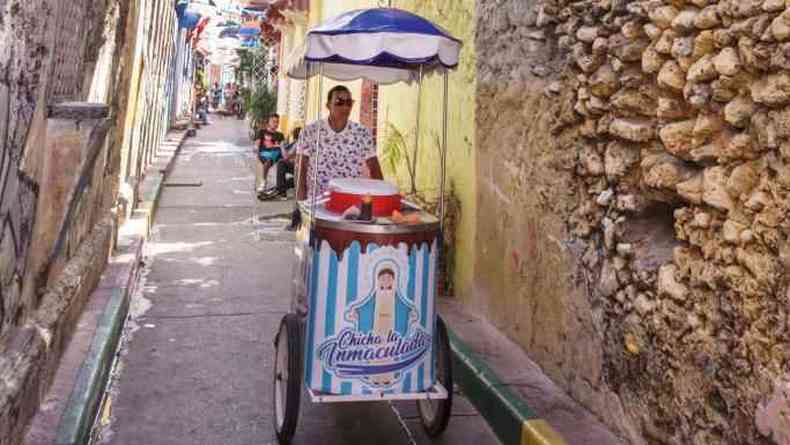 Homem empurrando carrinho de venda por rua