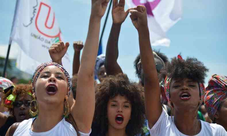 Mulheres negras em protesto com as mos para o alto com o punho fechado