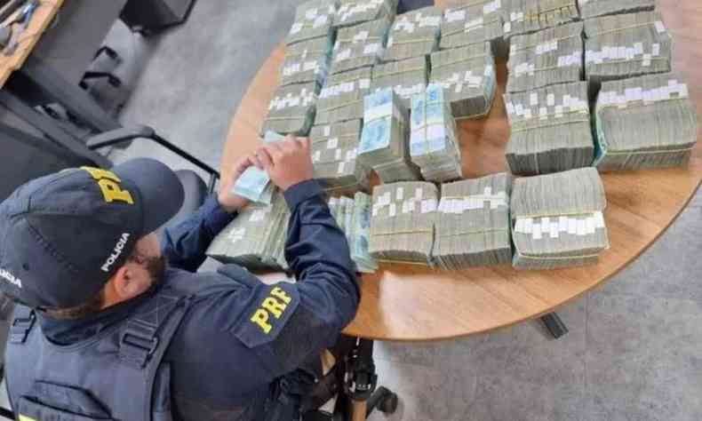 Polcia federal diante de grande quantidade de dinheiro em uma mesa