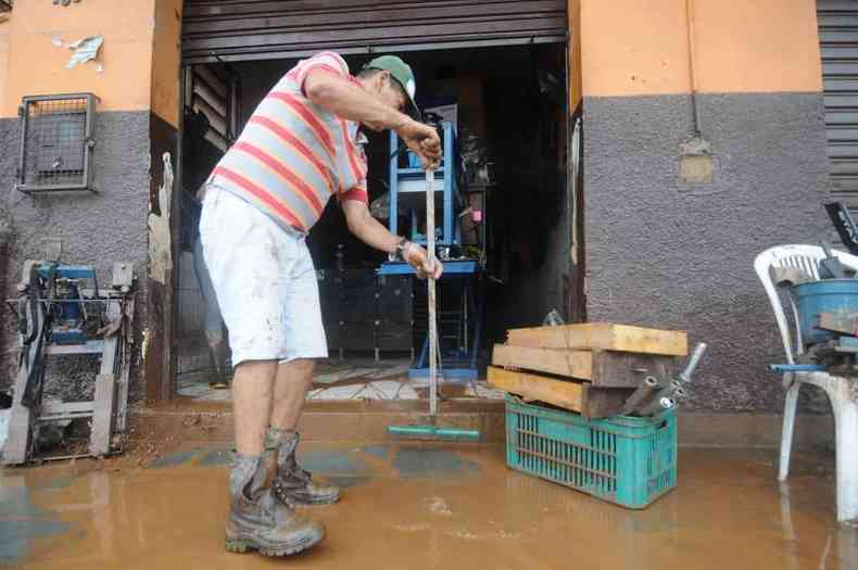 Morador de Sabar limpando comrcio que foi inundado pelo Rio das Velhas